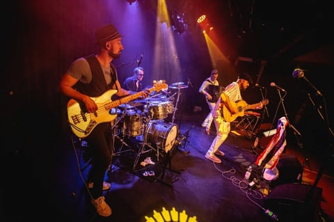 Live band on stage with purple and red lighting