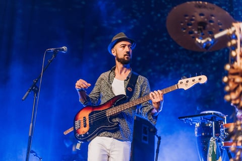 Musician with fedora playing bass guitar with microphone