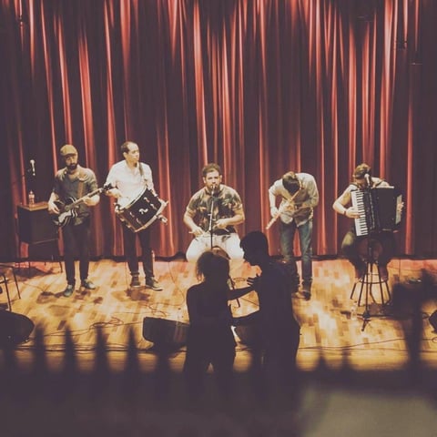 Five musicians with accordion and brass on stage