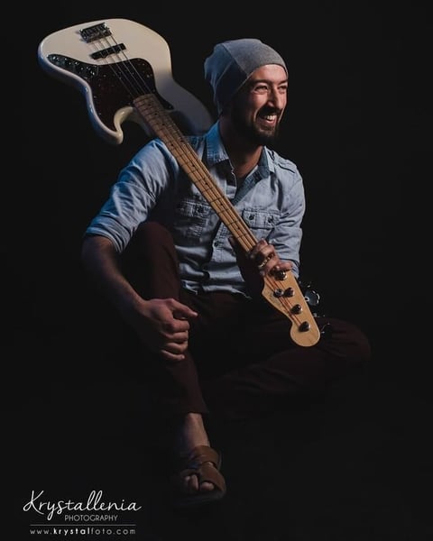 Musician with blue beanie holding electric bass guitar